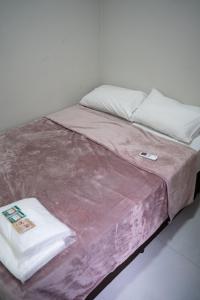 a bed with a pink blanket and pillows on it at Casa 2 Quartos com Ar até 8 Pessoas Jd. Sabiás in Indaiatuba