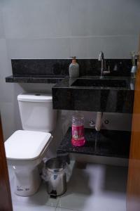 a bathroom with a white toilet and a sink and a sink at Casa 2 Quartos com Ar até 8 Pessoas Jd. Sabiás in Indaiatuba