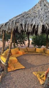 a straw hut with cushions under it on the beach at منتجع سفاري ديور in At Turbīyah