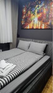 a bed with striped pillows and a painting on the wall at Amara in Zlatibor