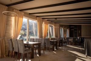 a dining room with tables and chairs and windows at Casa Ina in Moisei