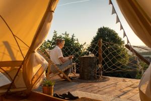 a man sitting in a chair on a deck in a tent at Glamping Ty Západy in Stanový +21 photos