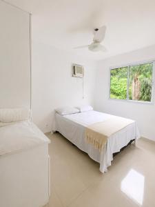 two beds in a white room with a window at Porto Real Resort Suítes in Mangaratiba +49 photos