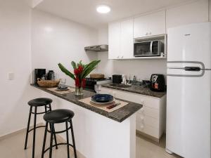 a kitchen with white cabinets and a counter with stools at Porto Real Resort Suítes in Mangaratiba