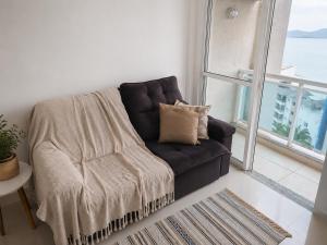 a black couch in a living room with a window at Porto Real Resort Suítes in Mangaratiba