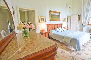 a bedroom with a bed and a vase of flowers on a table at Villa Bellavista - Tuscany panoramic view in Crespina