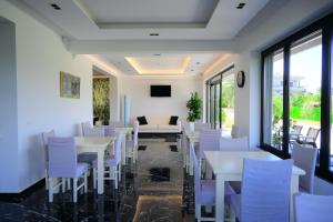 a dining room with white tables and chairs at Golden Berden Boutique Apart-Hotel in Sarandë