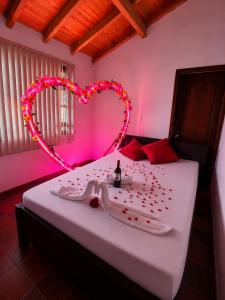 a bedroom with a heart shaped bed with a bottle of champagne at Hotel Lancers in Paipa