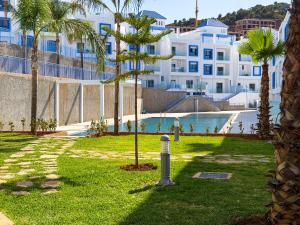 a park with palm trees and a building at Résidence Oscar - Pool & View in M'diq