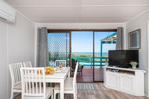 a dining room with a white table and a television at Blue View - Ocean Views For Miles in Guilderton