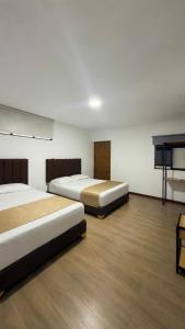 a room with two beds and a television in it at Hotel Gallery By 70 in Medellín