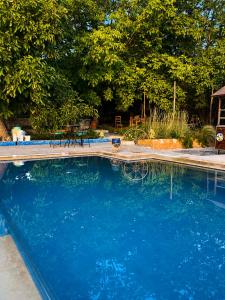 a swimming pool with blue water in a yard at Villa Mouloud - Piscine partagée, nature et calme in Khenifra