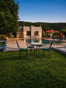 a table and chairs in the grass next to a pool at Villa Mouloud - Piscine partagée, nature et calme in Khenifra