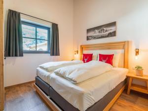 a bedroom with a large bed with red pillows at Almrausch in Wald im Pinzgau