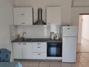a kitchen with white cabinets and a white refrigerator at Apartments by the sea Ugljan - 846 in Ugljan +25 photos
