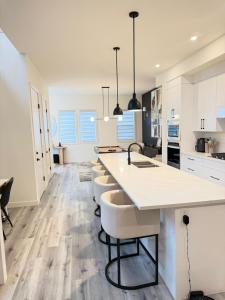 a kitchen with white cabinets and a counter with stools at Emerald - 10mins from Stampede Park in Calgary