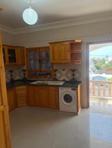 a kitchen with wooden cabinets and a washing machine at Résidence Djerba Oasis in Mezraya