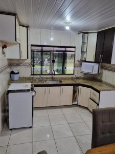 an empty kitchen with a sink and a microwave at Casa Da Chácara in Prudentópolis