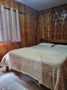 a bedroom with a bed and wooden walls at Casa Da Chácara in Prudentópolis