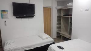 a room with two beds and a flat screen tv at HOTEL ALMARr in Coveñas