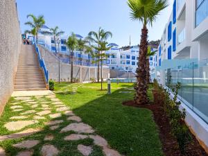 a pathway with palm trees next to a building at Résidence Oscar - Pool & View in M'diq