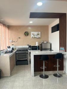 a kitchen with a stove and a counter with bar stools at Departamento en el CENTRO DE XALAPA 2habitaciones GARAGE INCLUIDO in Xalapa