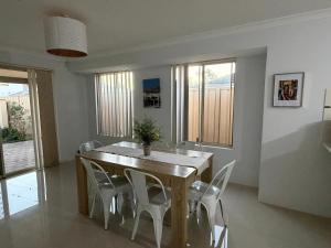 a dining room with a wooden table and white chairs at Sweet Single in Wellard