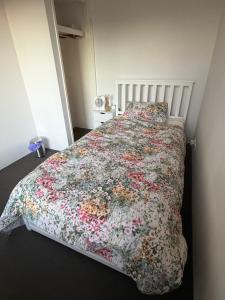 a bedroom with a large bed with a floral bedspread at Sweet Single in Wellard