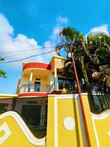 a yellow building with a palm tree in front of it at EDEN PALACE KIGALI AIRPORT AND APARTMENTs in Kigali