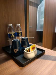 a black tray with two cups and bottles of soda at The Jerai Hotel Sungai Petani in Sungai Petani