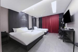 a hotel room with a large white bed and a desk at Hotel Zam 101 in Busan