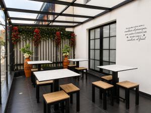 a row of tables and benches in a room with flowers at Hotel Embajada 44 in Bogotá