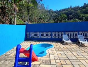 a pool with a slide and two chairs on a patio at Chácara sol nascente in Suzano