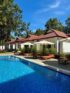 a resort with a swimming pool with benches and umbrellas at Kep Queen Boutique in Phumĭ Ŏng Char