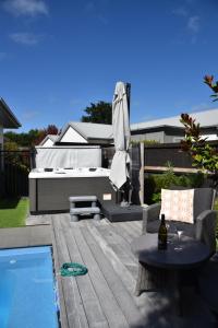 a patio with a pool and a umbrella and a table at Rojan's Roost in Christchurch