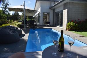 a bottle of wine on a table next to a swimming pool at Rojan's Roost in Christchurch