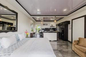 a bedroom with a large white bed and a kitchen at Vista del Pacifico Boutique Hotel in Quepos