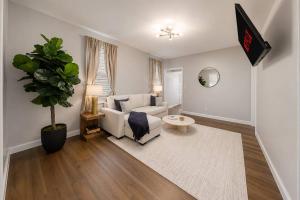 a living room with a white couch and a plant at Spacious 10BD Home, 12 min NYC & MetLife in Bayonne