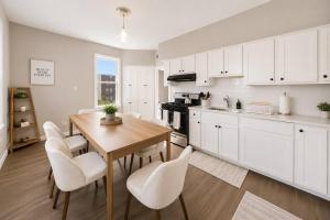 a kitchen with a wooden table and white cabinets at Spacious 10BD Home, 12 min NYC & MetLife in Bayonne