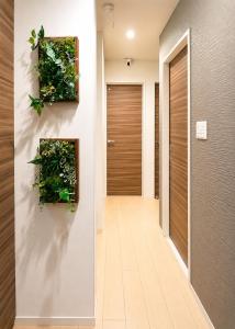 a hallway with a door with plants on the wall at Rest one room大阪-阪急梅田駅から電車と徒歩で15分-神崎川駅から徒歩7分- in Osaka