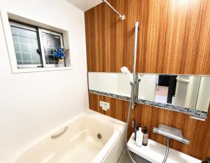 a bathroom with a white tub and a window at Rest one room大阪-阪急梅田駅から電車と徒歩で15分-神崎川駅から徒歩7分- in Osaka