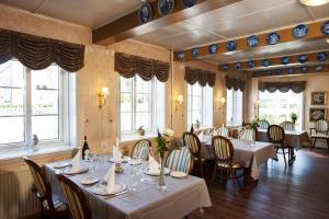 una sala da pranzo con tavoli e sedie bianchi e finestre di Hotel Bov Kro a Padborg