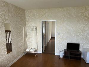 a living room with a television and a wall with wallpaper at Pension Sora in Nachikatsuura