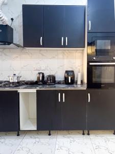a kitchen with black cabinets and a counter top at Oak Atlantic Layout - OTITO Suites in Lekki