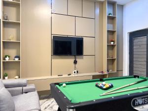 a living room with a pool table and a tv at Oak Atlantic Layout - OTITO Suites in Lekki