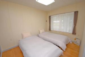 two beds in a small room with a window at 民宿やまのほ in Engaru