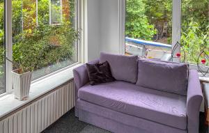 a purple couch sitting in a room with windows at 2 Bedroom Pet Friendly Home In Ringkøbing in Ringkøbing