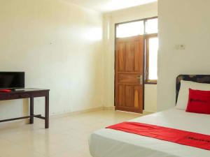 a bedroom with a bed and a desk and a window at RedDoorz @ Malalayang Manado in Manado
