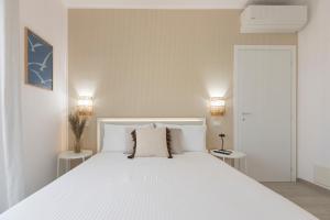 a white bedroom with a large white bed with two tables at Dimore Margherita in Petacciato