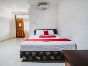 a bedroom with a large bed with a red pillow at RedDoorz @ Malalayang Manado in Manado